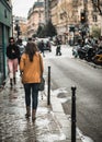 A woman walks on the sidewalk in Paris after the rain