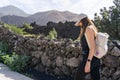 woman walks smiling looking at the ground in front of a volcano