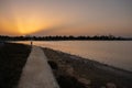 A woman walks at sunset along a footpath on Larnaca salt lake shore with the Hala Sultan Tekke mosque in the background Royalty Free Stock Photo