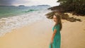 Woman walks to the stormy cloudy ocean on sand beach. Girl in blue swimsuit dress tunic. Concept rest in sea, tropical Royalty Free Stock Photo