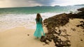 Woman walks to the stormy cloudy ocean on sand beach. Girl in blue swimsuit dress tunic. Concept rest in sea, tropical Royalty Free Stock Photo