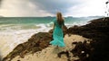 Woman walks to the stormy cloudy ocean on sand beach. Girl in blue swimsuit dress tunic. Concept rest in sea, tropical Royalty Free Stock Photo