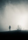 A woman walks towards the sun in the blown fog on top of a mountain on a cold winter day in southern France Royalty Free Stock Photo