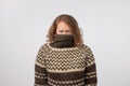 Woman in warm brown sweater hiding her face. Only eyes are seen. She wants to stay anonym. Royalty Free Stock Photo