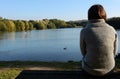 Woman in a warm jumper sitting alone by a lake Royalty Free Stock Photo