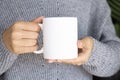 Woman in warm sweater holding white mug in hands. Winter cup Mockup for Christmas individual gifts design Royalty Free Stock Photo