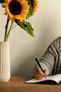 Woman writing in notebook at inspirational workplace with beautiful sunflowers