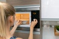 Woman warm up the food in microwave oven at home