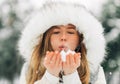 Woman in warm winter clothes, Winter woman blowing snow in the park, throwing snow into the air on a sunny winter day