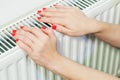 Woman warming hands on heating radiator