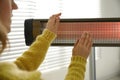 Woman warming hands near electric infrared heater indoors, closeup Royalty Free Stock Photo
