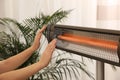 Woman warming hands near electric infrared heater indoors, closeup Royalty Free Stock Photo