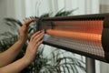 Woman warming hands near electric infrared heater indoors, closeup Royalty Free Stock Photo