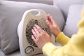 Woman warming hands near fan heater indoors, closeup Royalty Free Stock Photo