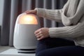 Woman warming hands near heater on floor. Generate Ai Royalty Free Stock Photo