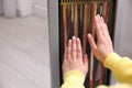 Woman warming hands near heater indoors, closeup Royalty Free Stock Photo