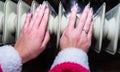 Woman warming up her hands on a white radiator Royalty Free Stock Photo