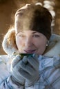 Woman warms frozen hands wearing gloves, close up facial portrait