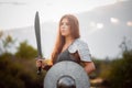 A woman warrior with combat makeup in a chainmail top with plate shoulder pads and bracers poses in a combat Royalty Free Stock Photo