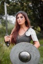 A woman warrior with combat makeup in a chainmail top with plate shoulder pads and bracers poses in a combat Royalty Free Stock Photo