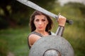 A woman warrior with combat makeup in a chainmail top with plate shoulder pads and bracers poses in a combat Royalty Free Stock Photo