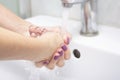 Woman washes hands with soap in the bathroom.