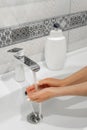 Woman washes her hands in the bathroom with special soap. Personal care and hygiene.
