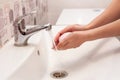 A woman washes her hands with soap in a white sink in the bathroom. Royalty Free Stock Photo