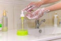 Woman washes his hands with liquid soap from a bottle. COVID-19 Hygiene concept. Washing hands with soap under the faucet with