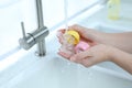 Woman washing baby bottle nipples under stream of water, closeup