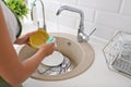 Woman washing dirty dishes in kitchen sink