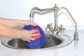 Woman washing dishes in the sink. She has a cleaning sponge in her hand Royalty Free Stock Photo