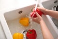 Woman washing fresh bell peppers in kitchen sink, closeup Royalty Free Stock Photo