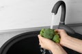 Woman washing fresh green broccoli in kitchen sink. Space for text Royalty Free Stock Photo