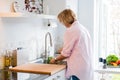 Woman washing fresh raw broccoli under running water over sink on her kitchen. Preparing food ingredients for lunch Royalty Free Stock Photo