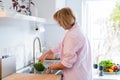 Woman washing fresh raw broccoli under running water over sink on her kitchen. Preparing food ingredients for lunch Royalty Free Stock Photo