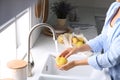 Woman washing fresh ripe pear in kitchen Royalty Free Stock Photo