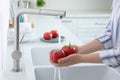 Woman washing fresh ripe tomatoes under tap water in kitchen, closeup Royalty Free Stock Photo