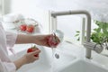 Woman washing fresh ripe tomatoes under tap water in kitchen, closeup Royalty Free Stock Photo