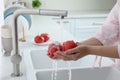 Woman washing fresh ripe tomatoes under tap water in kitchen, closeup Royalty Free Stock Photo