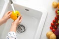 Woman washing fresh yellow bell pepper in kitchen sink, top view Royalty Free Stock Photo
