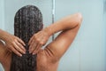 Woman washing hair in shower under water jet