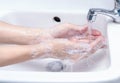 Woman washing hand with soap foam and tap water in bathroom. Hand clean under faucet on sink for personal hygiene to prevent flu Royalty Free Stock Photo