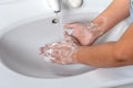 Woman washing hand with soap foam and tap water in bathroom. Hand clean under faucet on sink for personal hygiene to Royalty Free Stock Photo