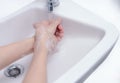 Woman washing hand with soap foam and tap water in bathroom. Hand clean under faucet on sink for personal hygiene to prevent flu Royalty Free Stock Photo