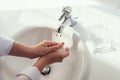 Woman washing hands rubbing with soap in white sink in bathroom with sunlight from the window. Protection from bacteria and virus. Royalty Free Stock Photo