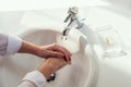 Woman washing hands rubbing with soap in white sink in bathroom with sunlight from the window. Protection from bacteria and virus. Royalty Free Stock Photo