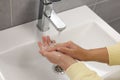 Woman washing hands with water from tap in bathroom, closeup Royalty Free Stock Photo