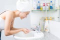 Woman washing her face with water above bathroom sink. Royalty Free Stock Photo