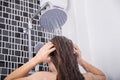 Woman is washing her hair and face by rain shower, rear view Royalty Free Stock Photo